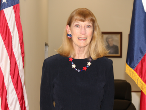 Image of Commissioner Precinct 3 - Pat Rousseau; between American and Texas Flags